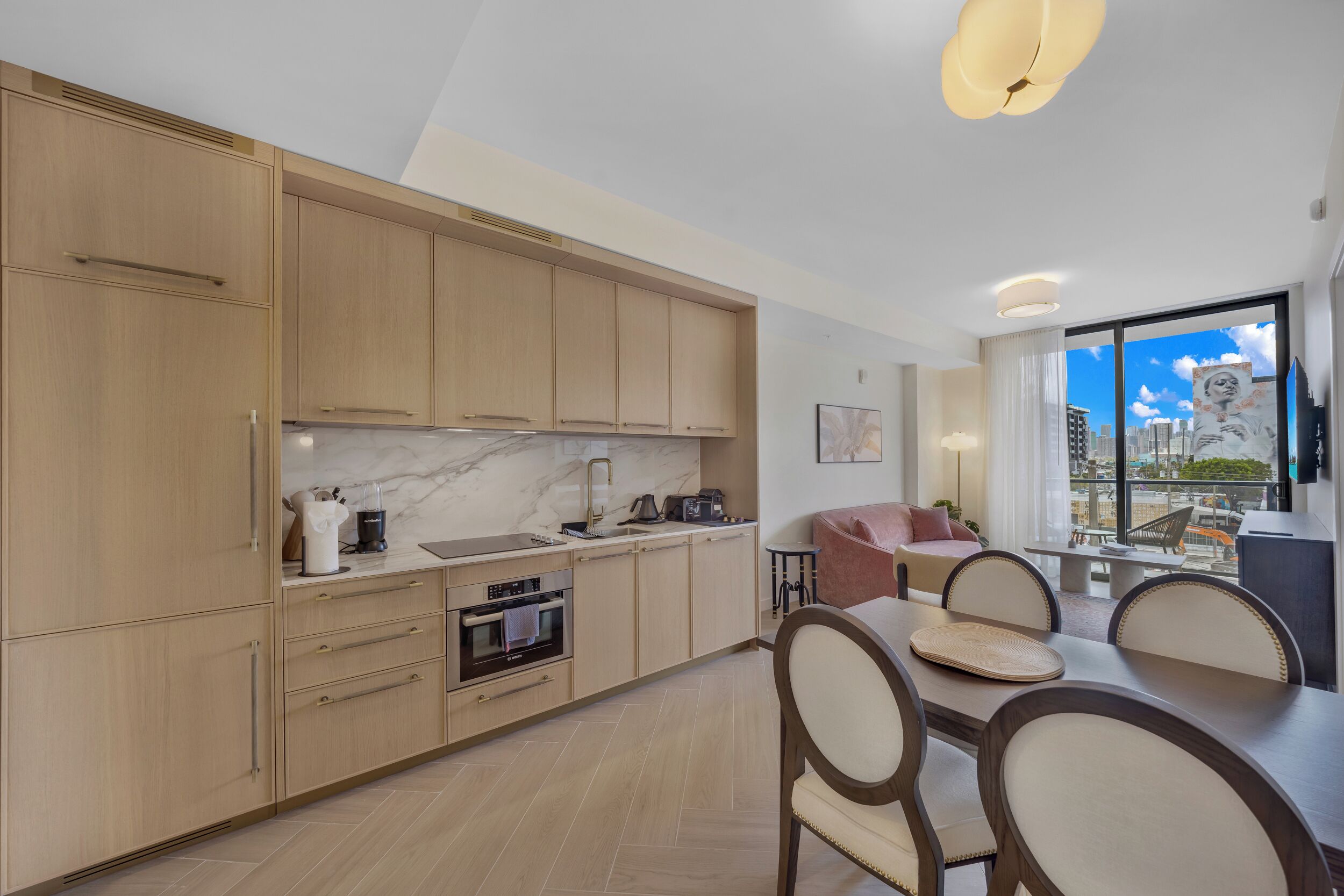 A modern kitchen with wooden cabinets, a marble backsplash, and a dining area with a table and chairs.