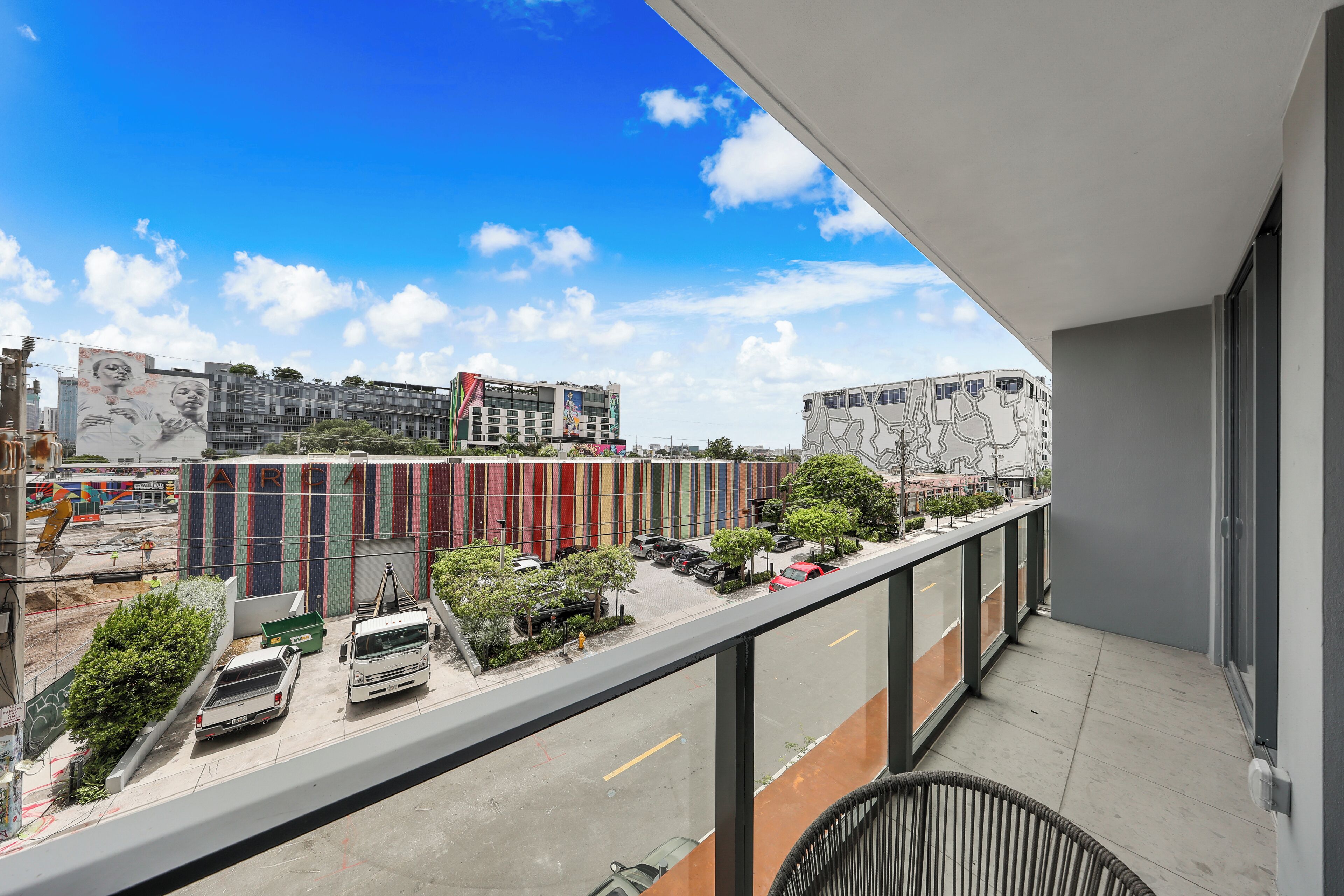 A balcony with a view of a parking lot, buildings, and a clear sky.