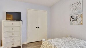 Un dormitorio con cama, cómoda, armario y una obra de arte colgada en la pared.