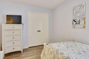Ein Schlafzimmer mit einem Bett, einem Schminktisch, einem Kleiderschrank und einem Wandbild.