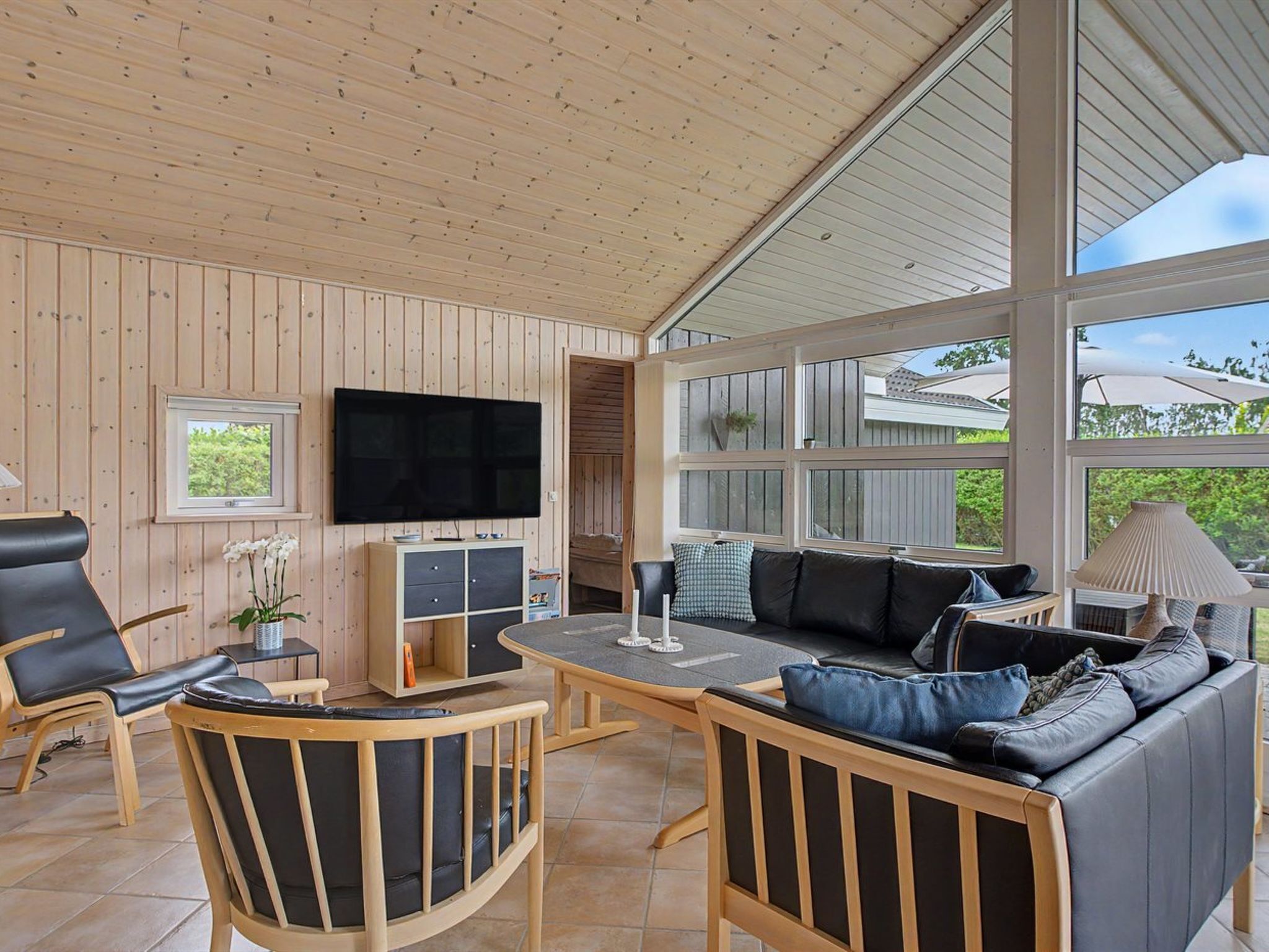 Un vaste espace de vie avec des murs en bois, un téléviseur à écran plat, un canapé et une table à manger.