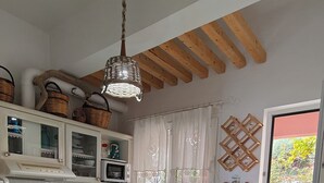 Una cocina con armarios blancos, estufa, lavaplatos e iluminación colgante.