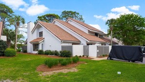 Ein zweistöckiges Haus mit Ziegeldach, weißen Außenwänden und einem überdachten Stellplatz in der Einfahrt.