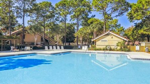 Ein Pool mit Liegestühlen, umgeben von Bäumen und Gebäuden.