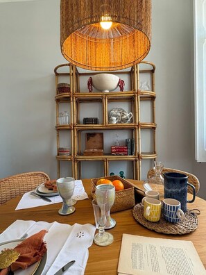 A dining table with a basket of oranges, a pitcher, and a book. - Casa Fataca (Grândola)