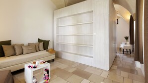 A modern living room with a sofa, a small table with toys, and a white shelving unit. - Masseria Corda di Lana - Suite Deluxe (Leverano)