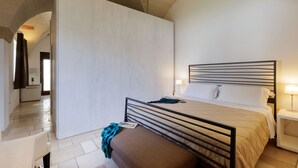 A bedroom with a bed, bedside tables, a bench, and an arched ceiling. - Masseria Corda di Lana - Suite Deluxe (Leverano)