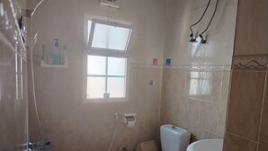 Une salle de bain équipée d’une douche, de toilettes, d’un lavabo et d’une fenêtre.