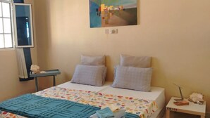 Une chambre à coucher avec un lit, des oreillers, un tableau, une table de chevet et un tapis.