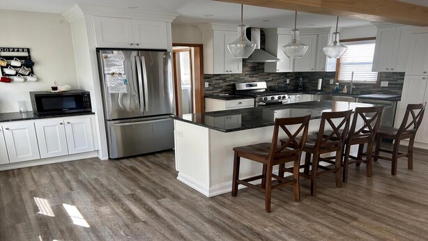 Una cocina moderna con un refrigerador de acero inoxidable, un horno empotrado y una isla central con taburetes de bar.