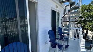 Una terraza con sillas Adirondack azules, una escalera en espiral y una barandilla blanca.