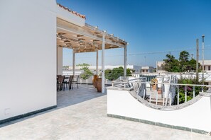 Une terrasse sur le toit agrémentée d’une pergola, de sièges d’extérieur et de plantes en pot.