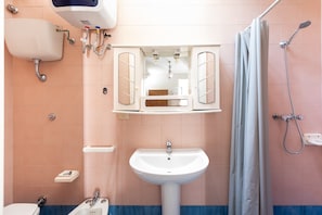 A bathroom with a sink, mirror, shower, and toilet.