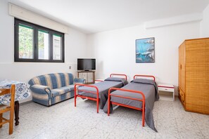A room with a sofa, two single beds, a television, a cabinet, and a window. - Apartment 'Villa Ruggieri - Semiterra' with Private Terrace and Garden (Melendugno)
