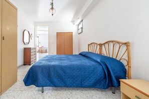 A bedroom with a bed, wooden wardrobe, and a small bedside table. - Apartment 'Villa Ruggieri - Semiterra' with Private Terrace and Garden (Melendugno)