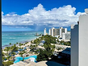 A resort with a pool, palm trees, and a view of the ocean and buildings. - Isla Verde Beach/Self Check-in, 1 Parking, Pool (Carolina)