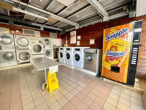 A laundromat with multiple washing machines, a table, and a Snapple iced tea vending machine. - Isla Verde Beach/Self Check-in, 1 Parking, Pool (Carolina)