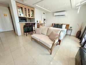 A modern living room with a sofa, a dining area with chairs, and a kitchen with cabinets. - Isla Verde Beach/Self Check-in, 1 Parking, Pool (Carolina)