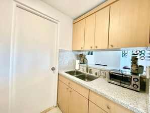 A kitchen with a double sink, a toaster, and wooden cabinets. - Isla Verde Beach/Self Check-in, 1 Parking, Pool (Carolina)