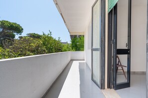 A balcony with a white railing, a glass door, and a view of trees and buildings. - Apartment 'Villa Ruggieri - Terra' with Private Terrace, Garden and Air Conditioning (Melendugno)