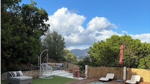 Een zwembad met ligbedden, lounge stoelen en een pergola met parasol.