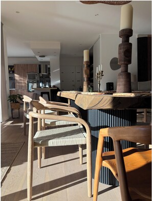 Eine moderne Küche mit Holzausstattung, einem eingebauten Ofen und einem Essbereich mit Holztisch und Stühlen.
