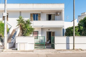 Un edificio de dos pisos con balcón, escaleras y una reja.