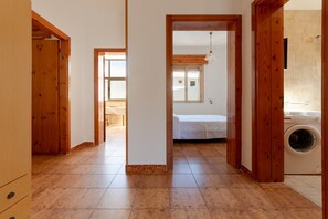 Un pasillo con puertas de madera, una cama y una lavadora.