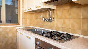 A kitchen with a gas stove, stainless steel sink, and white cabinets. - Apartment 'Villa Mezzaluna - Cielo' with Balcony and Air Conditioning (San Foca)