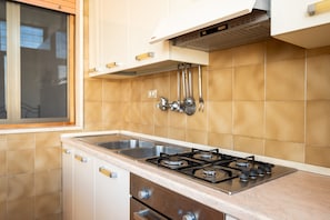 A kitchen with a gas stove, stainless steel sink, and white cabinets. - Apartment 'Villa Mezzaluna - Cielo' with Balcony and Air Conditioning (San Foca)