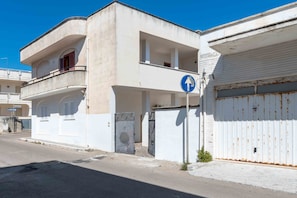 Un edificio de dos pisos con un balcón, un garaje y un cartel azul de indicaciones.