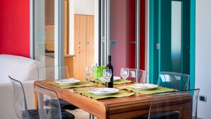 A dining area with a wooden table, clear glass chairs, and a bottle of wine. - Apartment 'Terrazza Sul Mare' with Sea View, Private Terrace and Air Conditioning (San Foca)