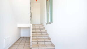 A staircase with a handrail, leading to a landing with a window. - Apartment 'Terrazza Sul Mare' with Sea View, Private Terrace and Air Conditioning (San Foca)