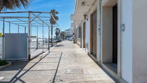 A narrow urban street with a metal structure, closed shop fronts, and a clear sky. - Apartment 'Terrazza Sul Mare' with Sea View, Private Terrace and Air Conditioning (San Foca)