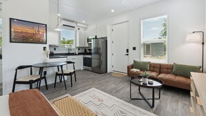 Ein modernes Wohnzimmer mit einem braunen Sofa, einem Couchtisch und einem Essbereich mit Stühlen.