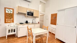 Uma cozinha compacta com área de refeições, piso de madeira e um guarda-roupa branco.
