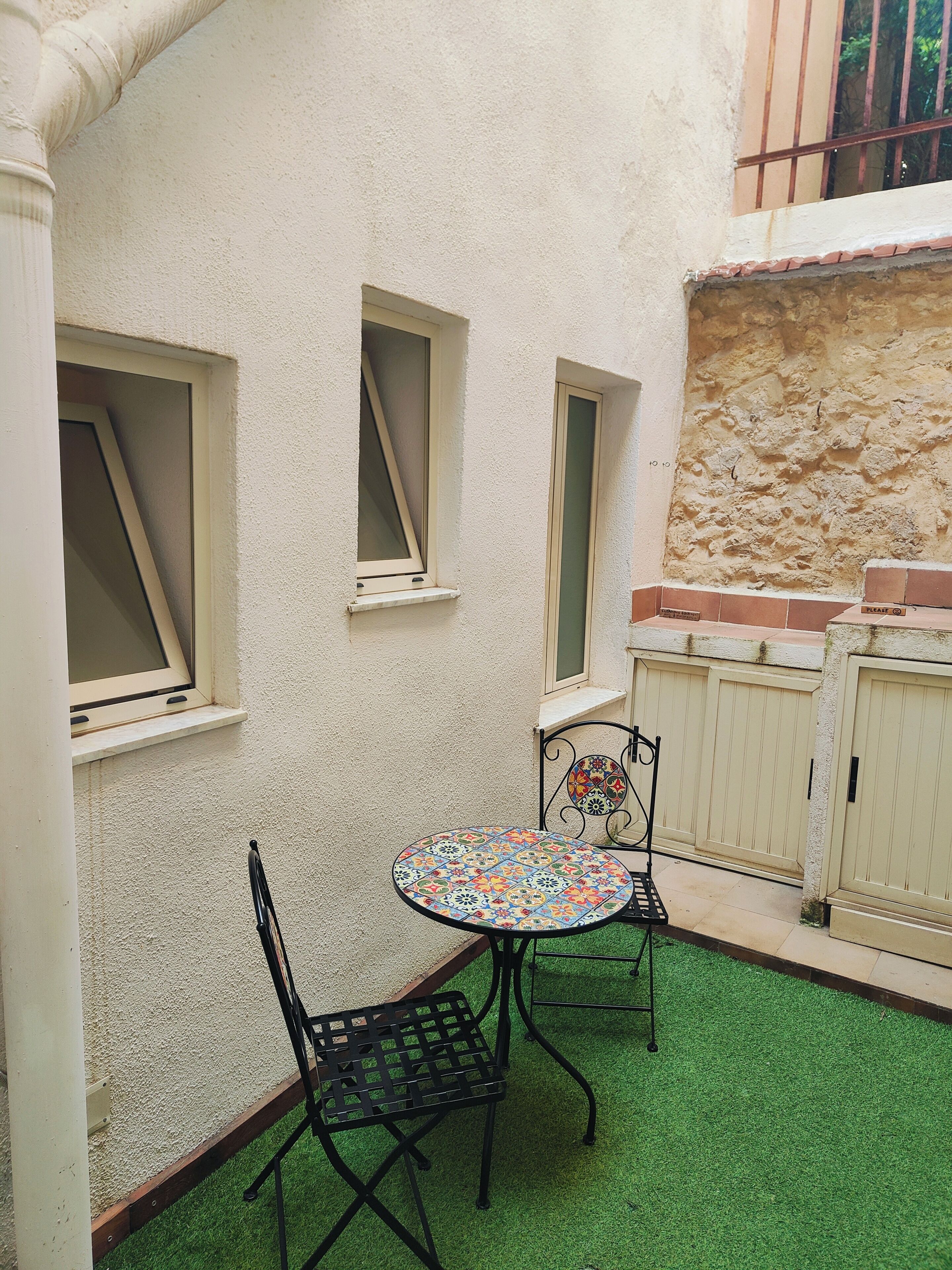 A small patio with a round table, two chairs, and a decorative wall.