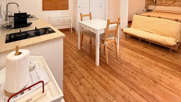 Um espaço compacto com cozinha compacta, mesa de jantar, sofá e um guarda-roupa pequeno.