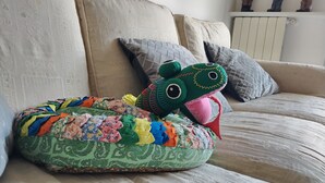 Ein Sofa mit einem farbenfrohen, gemusterten Kissen und einem grünen Plüschtier.