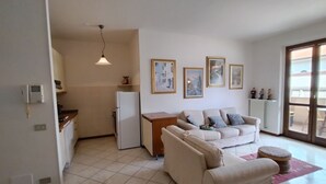 Ein Wohnzimmer mit einer Couch, einem kleinen Tisch und einer Küchenzeile mit Kühlschrank.