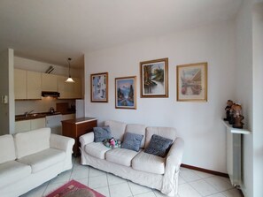 A living room with a sofa, a dining table, and a kitchen in the background. - Temporary Home Giussano Monza and Brianza (Giussano)