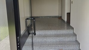 Ein Korridor mit Glastür, Treppe und einer braunen Fußmatte am unteren Ende.