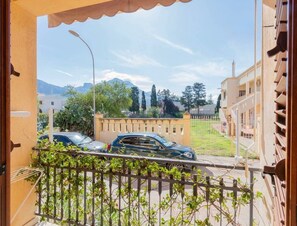 Uma varanda com vista para uma rua, um carro e edifícios ao fundo.