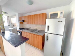 Eine kompakte Küche mit Holzausstattung, einer eingebauten Mikrowelle und einem Kühlschrank mit zwei Türen.
