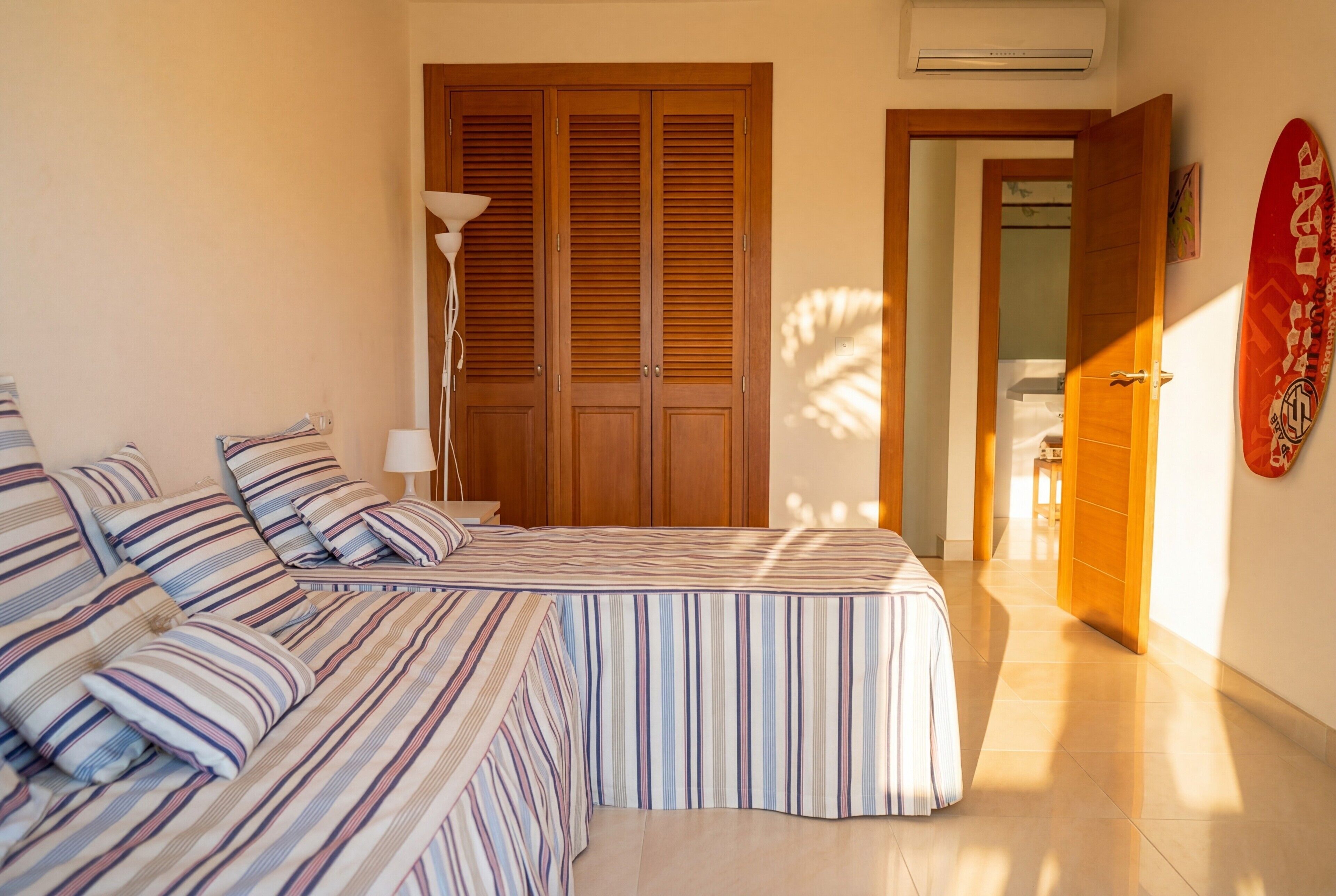 Una camera da letto con un letto, un comodino, una lampada, un armadio e una tavola da surf appesa al muro.