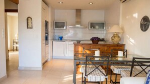 A modern kitchen with white cabinets, a glass dining table, and a wooden island. - Oasis Quitapenas Apartment Arroyo Marinos with Pool, Shared Terrace & Wi-Fi (Almuñécar)