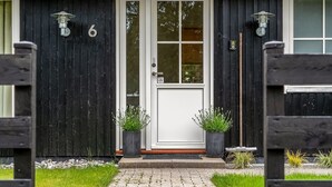 A house with a white door, black exterior walls, and two potted plants on the front porch. - "Linnea" -  from the sea by Interhome (Hals)