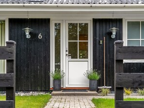 A house with a white door, black exterior walls, and two potted plants on the front porch. - "Linnea" -  from the sea by Interhome (Hals)