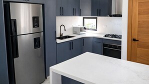 Een moderne keuken met een roestvrijstalen koelkast, een ingebouwde oven, een magnetron en een gasfornuis.