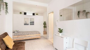 Un dormitorio moderno con cama, sofá, escritorio y espejo.
